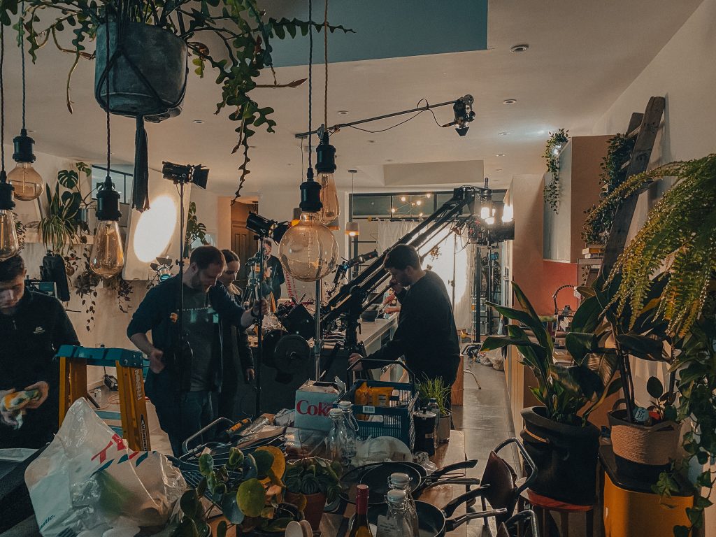 Wide shot of all the crew filming in the kitchen